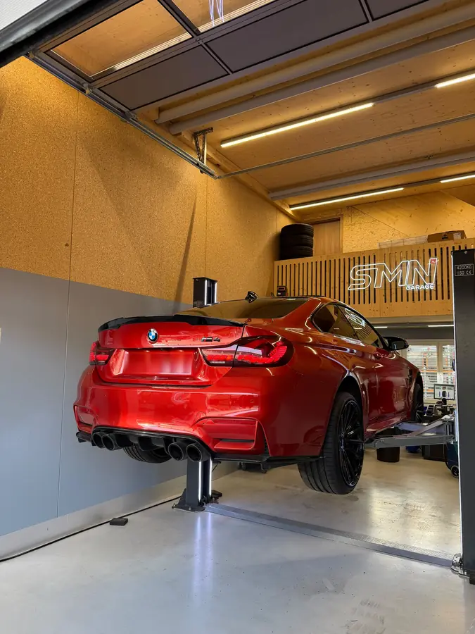 Roter BMW M4 mit schwarzen Felgen auf der Hebebühne